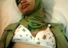 An amateur Indonesian babe, dressed in a jilbab, fingers herself in a hotel room, showcasing her Arab and Asian beauty.