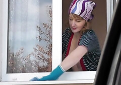 Blonde in black stockings cleans window then strips topless for exhibitionist show