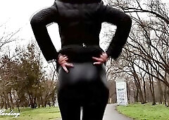 A cutie with a glamorous butt walks in an autumn park in leather panties and sometimes shows her bazookas