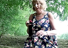 British blonde amateur solo granny Rosemary in colorful summer dress sitting on a tree trunk and playing with her shaved pussy outdoor