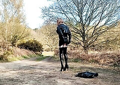 Crossdressed transvestite in pvc playing in forest car park