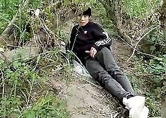 The cute gay twink jerking off his cock, pulled through his fly while outdoors, is Jon Arteen